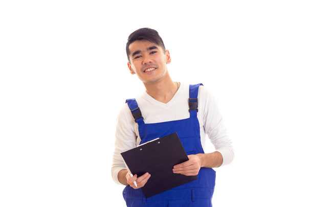 junger Mann in blauem Overall mit Stift und Mappe - Foto, Bild
