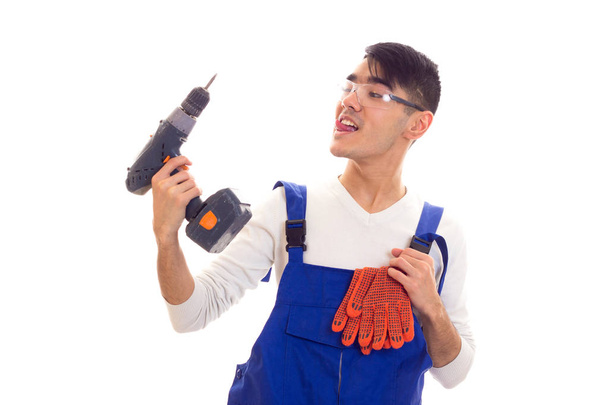Man in overall met handschoenen en bril houden van elektrische schroevendraaier - Foto, afbeelding