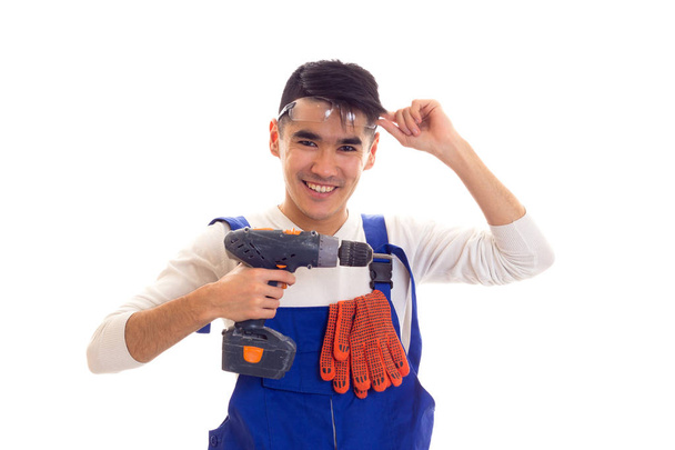 Man in overall with gloves and glasses holding electric screwdriver - Foto, afbeelding