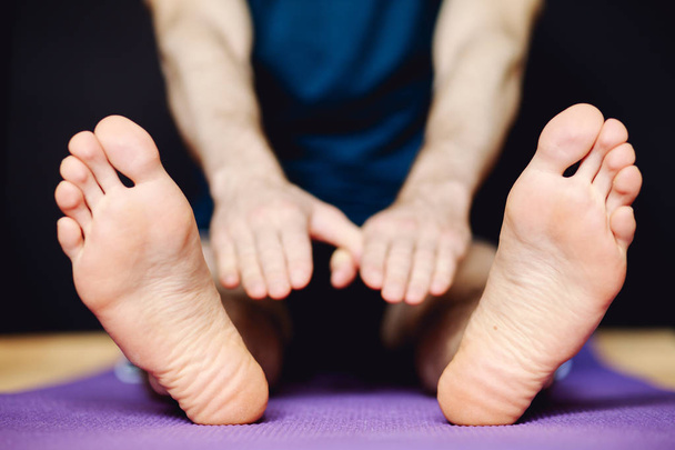 Man stretching his legs on floor mat - Zdjęcie, obraz