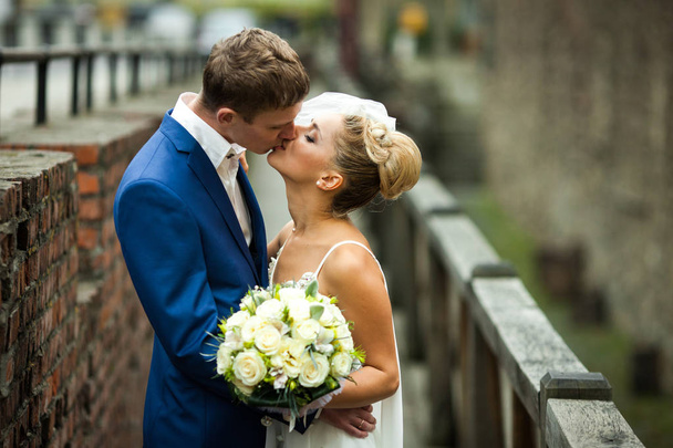 Stylish groom dressed in blue suit kisses an elegant bride - Foto, Imagen