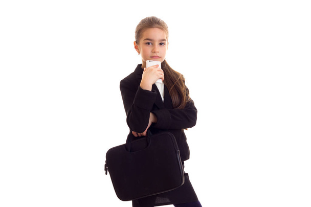 Little girl in black jacket holding diploma and smartphone - Foto, imagen