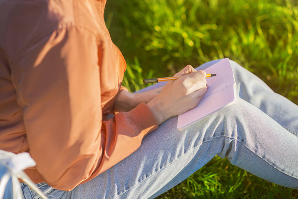 Woman sitting on the grass with her notebook - Фото, зображення