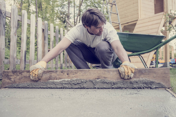 Man leveling the cement in a backyard - 写真・画像