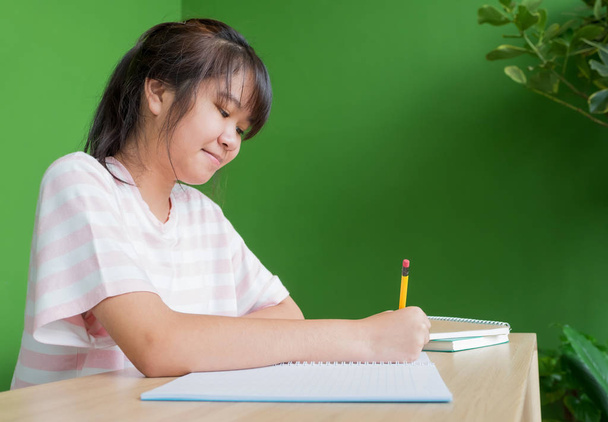 asian young teenager girl writing homework at school library tab - Foto, imagen