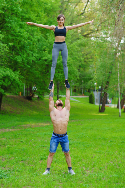 A guy and a girl are doing sports, aerial gymnastics in the park - Photo, Image