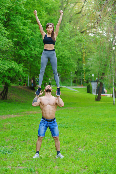A guy and a girl are doing sports, aerial gymnastics in the park - Valokuva, kuva