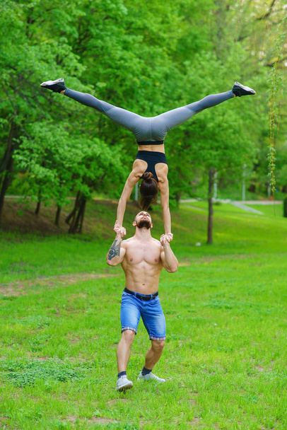 A guy and a girl are doing sports, aerial gymnastics in the park - Foto, imagen