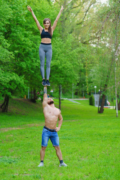 A guy and a girl are doing sports, aerial gymnastics in the park - Fotó, kép