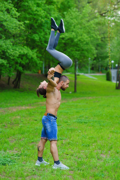 A guy and a girl are doing sports, aerial gymnastics in the park - Foto, afbeelding