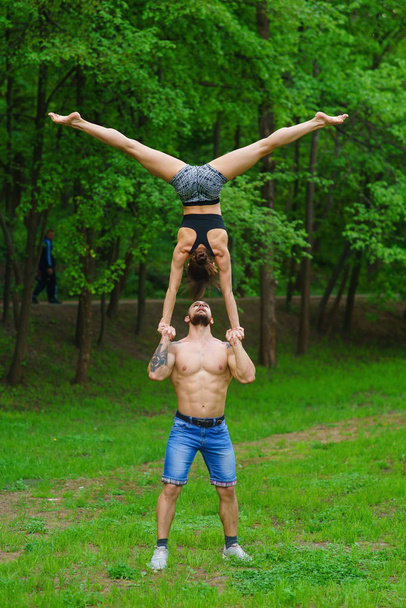 A guy and a girl are doing sports, aerial gymnastics in the park - Fotoğraf, Görsel