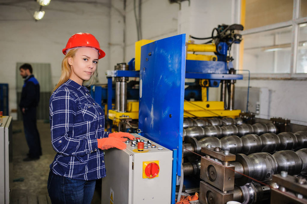 Frau mit rotem Schutzhelm arbeitet als Industriearbeiterin - Foto, Bild
