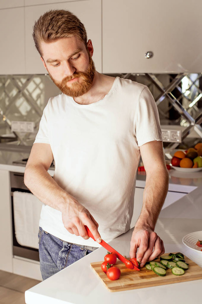 happy young man making a healthy salad in modern kitchen - Zdjęcie, obraz
