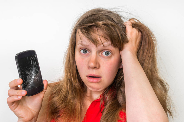 Sad woman is holding smartphone with broken screen - Zdjęcie, obraz
