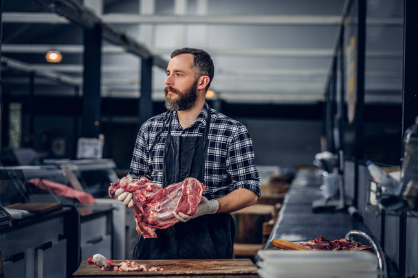 Мясник держит свежее мясо
 - Фото, изображение