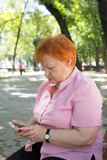 anziana donna sta chiamando per telefono nel parco della città
 - Foto, immagini