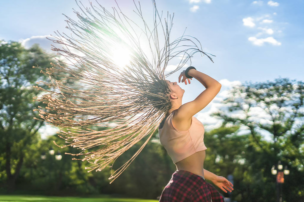 fille insouciante avec zizi cornrows dreadlocks danse sur la pelouse verte
 - Photo, image