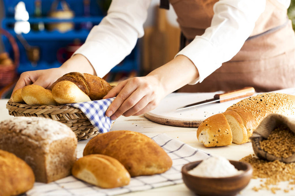 Γυναικεία χέρια εκμετάλλευσης φρέσκο ψωμί στο καλάθι - Φωτογραφία, εικόνα