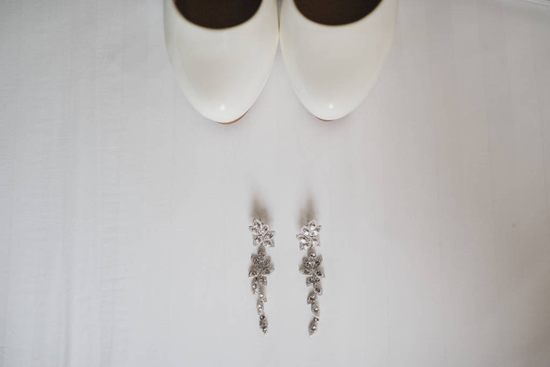 Doplňky nevěsta svatbu, náušnice bílé boty na bílém pozadí - Fotografie, Obrázek