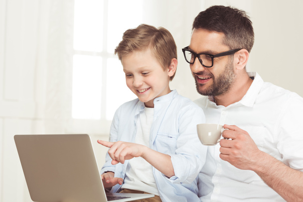 Vater benutzt Laptop mit Sohn zu Hause - Foto, Bild