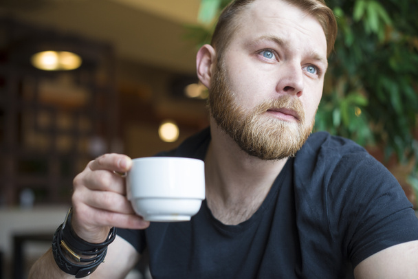 若い男が路上でコーヒーを飲む - 写真・画像