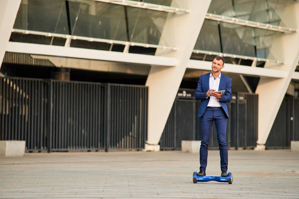 Young businessman on hoverboard outdoors. - Valokuva, kuva