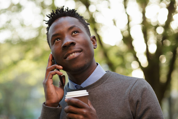 African american man talking by phone in sunny evening city - Photo, Image