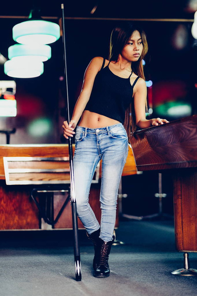 Young beautiful girl in a billiard club, with cue stick posing - Φωτογραφία, εικόνα