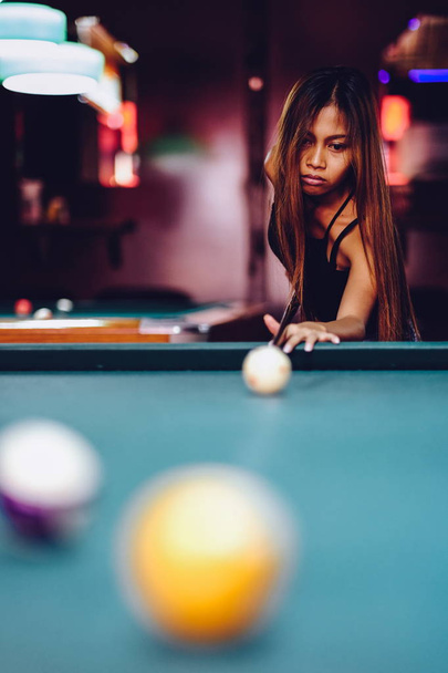 Young beautiful girl playing billiard in a club - Foto, afbeelding