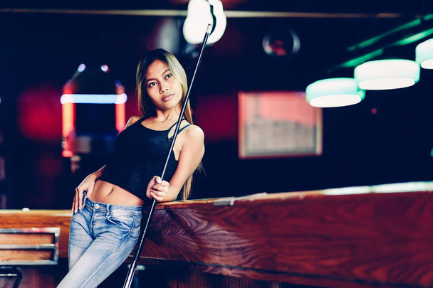 Young beautiful girl in a billiard club, with cue stick posing - Foto, Bild
