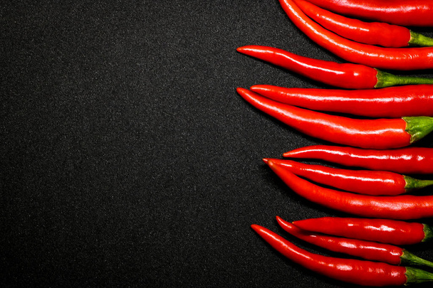 Rode chilipepers op zwarte achtergrond, verse hete chilipepers. - Foto, afbeelding
