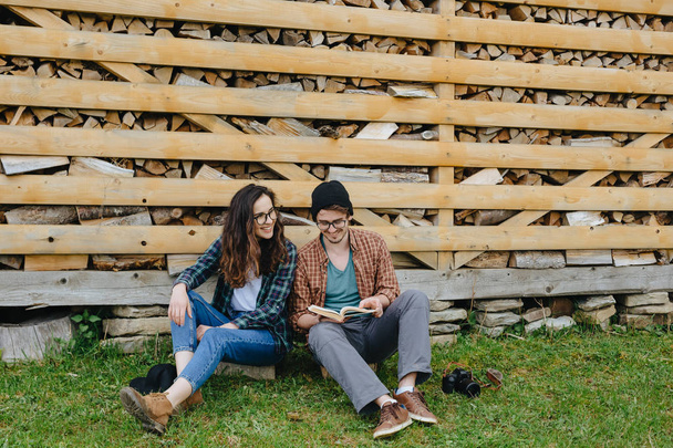 Couple of lovers looking each other outdoor. Woman and man in love sitting on the grass. Hipsters. Beautiful young couple. - Photo, Image