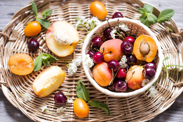 Fresh fruit apricots and cherries in wicker basket - Foto, immagini