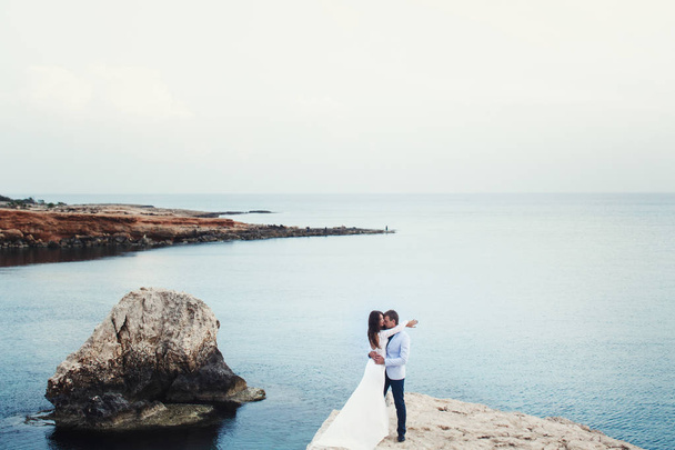 Azure sea spreads around a wedding couple hugging on the rock - Foto, Imagem