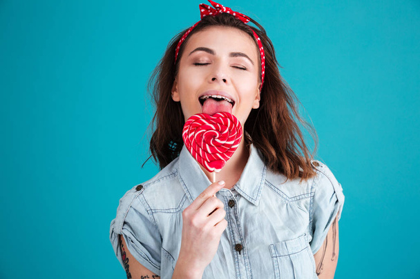 Happy woman standing isolated eating candy with eyes closed. - Foto, immagini
