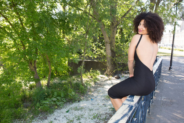 Όμορφο μοντέρνο κορίτσι με ένα μαύρο φόρεμα με μεγάλη λαιμόκοψη στο πίσω μέρος - Φωτογραφία, εικόνα