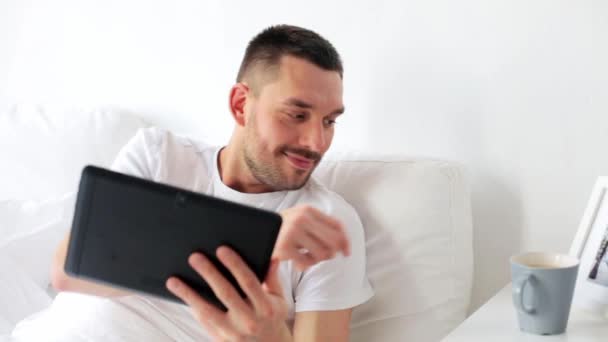 man with tablet pc drinking coffee in bed at home - Footage, Video