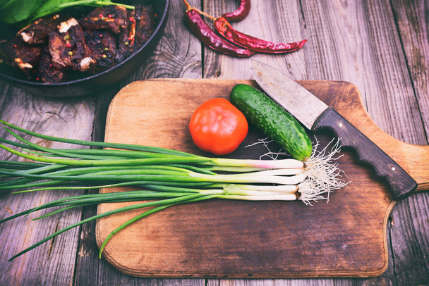 Oignons verts et légumes frais sur une planche à découper en bois
 - Photo, image