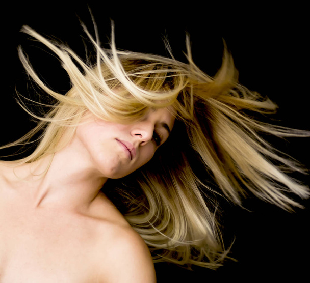 Portrait d'une belle femme secouant ses cheveux sur fond noir
 - Photo, image