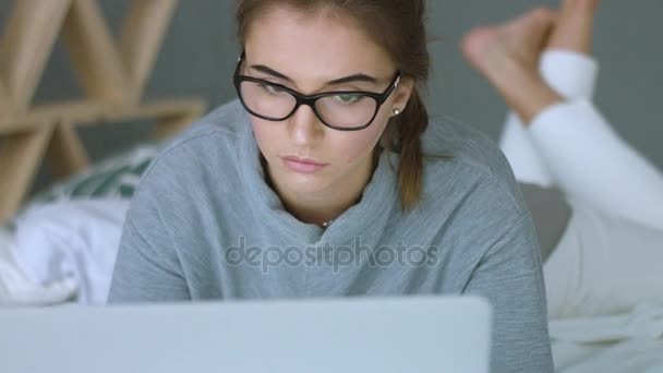 Young woman with glasses looking at the monitor, surfing the Internet - Séquence, vidéo