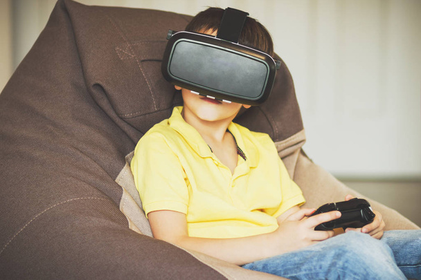 Boy plays game with virtual reality glasses indoors - Foto, afbeelding