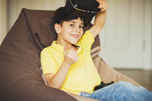 Boy plays game with virtual reality glasses indoors - Photo, Image