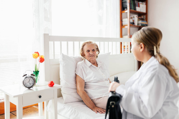 Proporcionar atención a los ancianos. Médico visitando paciente anciano en casa
.  - Foto, Imagen