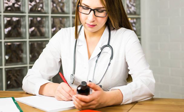 Zbliżenie: lekarz pisania receptę i trzymając butelkę z tabletkami. Opieki zdrowotnej, Medycyna i farmacja koncepcja. - Zdjęcie, obraz