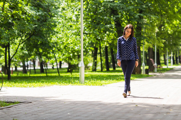 молодая женщина гуляла в зеленом летнем парке
 - Фото, изображение