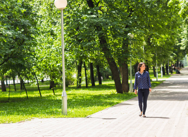 молодая женщина гуляла в зеленом летнем парке
 - Фото, изображение