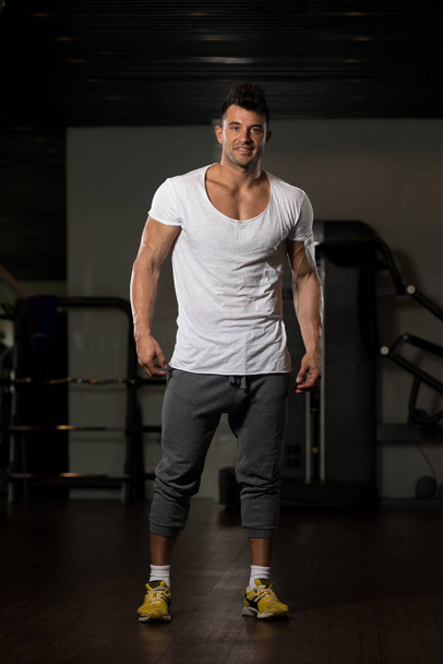 Strong Man in White T-shirt Background Gym - Фото, изображение