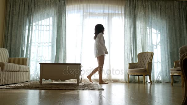 Ideges nő inget megy oda és vissza mentén a ablak-ból egy hangulatos apartman - Felvétel, videó