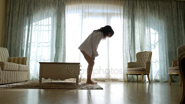 Αναστατωμένος γυναίκα σε πουκάμισο πηγαίνοντας εμπρός και πίσω κατά μήκος το παράθυρο από ένα άνετο διαμέρισμα - Πλάνα, βίντεο