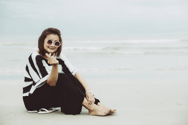 portret azjatycki pojedynczy hipster indy kobiety noszą okulary umiejscowienia na plaży zadowolony z ręki palec miłości znak vintage wyciszenia odcień. - Zdjęcie, obraz